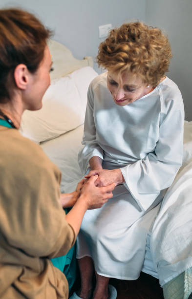 Female doctor giving encouragement to elderly patient by holding her hands